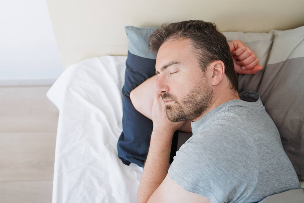 Uvolněný chlap spaní v posteli doma boční pohled - Fotografie, Obrázek