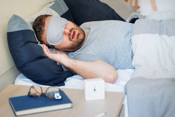 Uomo ritratto a letto indossando maschera occhio addormentato sentirsi a proprio agio - Foto, immagini