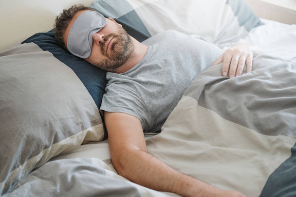 Un ragazzo che dorme e indossa una maschera per gli occhi - Foto, immagini
