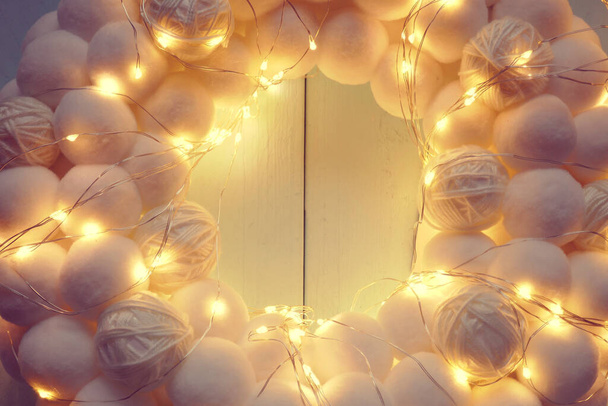 Noël, la couronne blanche du Nouvel An. couronne ronde de pompons doux blancs et guirlande brillante - Photo, image