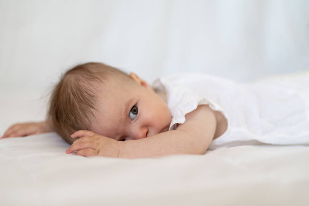 blank baby meisje als hij ligt op een pluizig naar beneden dekbed dekbed op een bed - Foto, afbeelding