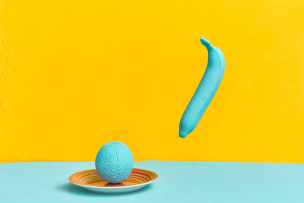 painted banana orange apple in turquoise color on a yellow background. creativity design concept - Photo, image