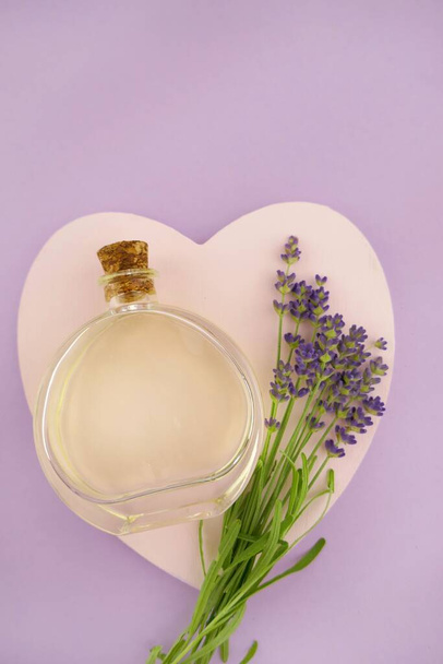 Olio essenziale di lavanda in bottiglia di vetro e fiori di lavanda su sfondo rosa e viola combinati - Foto, immagini
