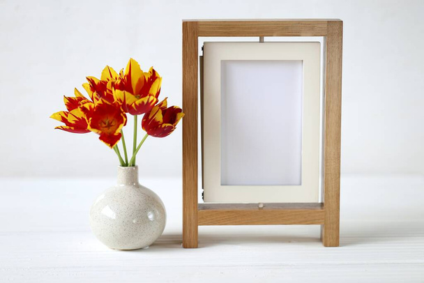 Floral frame.Flower card. Wooden frame and red tulips in a vase - Foto, imagen