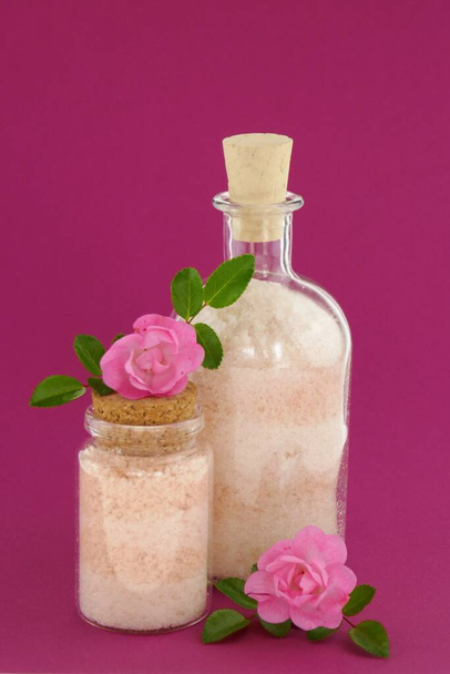 Sal marinho com extrato de rosa. Rosa Branco Camada Cosmético Banho Sal em uma garrafa de vidro
 - Foto, Imagem