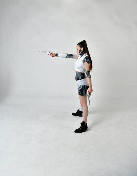 όμορφο κορίτσι με ρούχα ρομπότ ποζάρουν με ασημένια περίστροφα - Φωτογραφία, εικόνα
