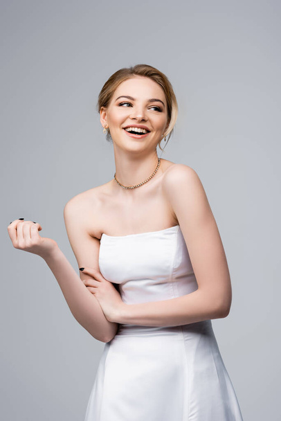 atrakcyjna panna młoda w białej sukni ślubnej śmiejąc się na szaro  - Zdjęcie, obraz
