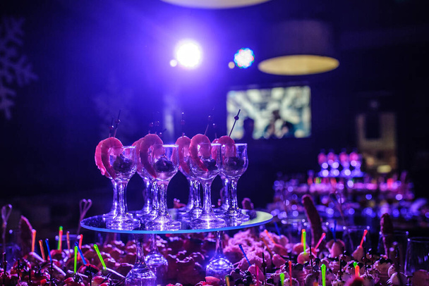 Buffet avec collations, canapés ; crevettes avec sauce dans des verres lors d'une fête d'anniversaire en lumières bleues - Photo, image