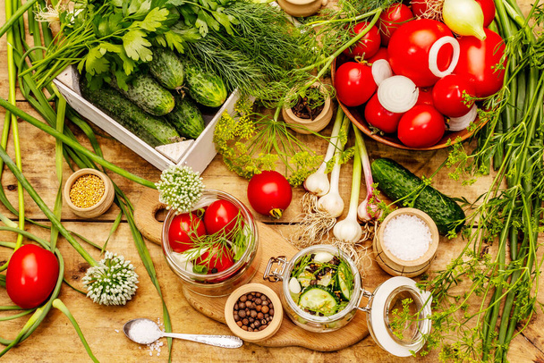 Pickling groente concept. Kookproces, kruiden, verse geurige kruiden. Rijpe tomaten en komkommers, oude houten tafel - Foto, afbeelding