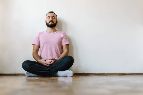 Stock photo of caucasian man sitting crossed legged meditating. He has his eyes closed. - Photo, Image