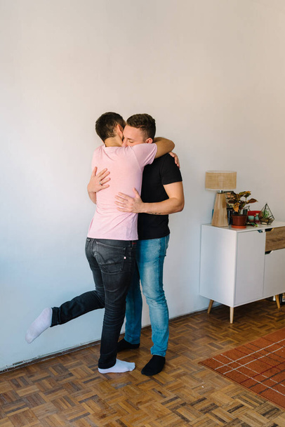 Archivbild von zwei kaukasischen homosexuellen Männern, die sich umarmen. Neben ihnen steht eine Schublade. - Foto, Bild