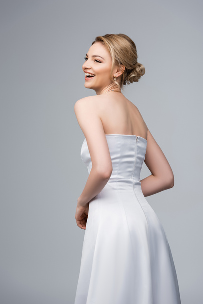 happy young bride in white wedding dress isolated on grey  - Zdjęcie, obraz