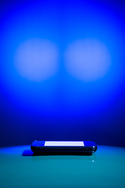 μοντέρνο κινητό τηλέφωνο βρίσκεται σε μια ημικυκλική επιφάνεια - Φωτογραφία, εικόνα