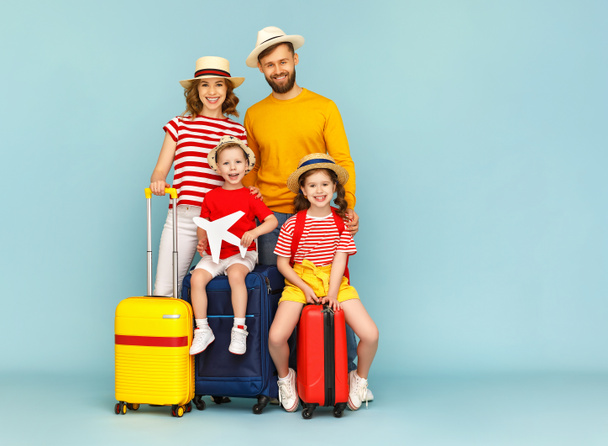 Corpo inteiro pais de família felizes e crianças com bagagem sorrindo e olhando para a câmera contra backdro azul
 - Foto, Imagem