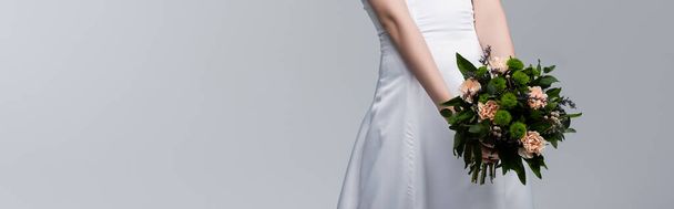 panoramic crop of bride in white wedding dress holding flowers isolated on grey  - Fotoğraf, Görsel