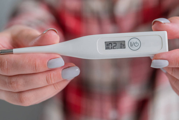 Frau zeigt medizinisches Thermometer mit hoher Körpertemperatur zu Hause - aus nächster Nähe - Foto, Bild