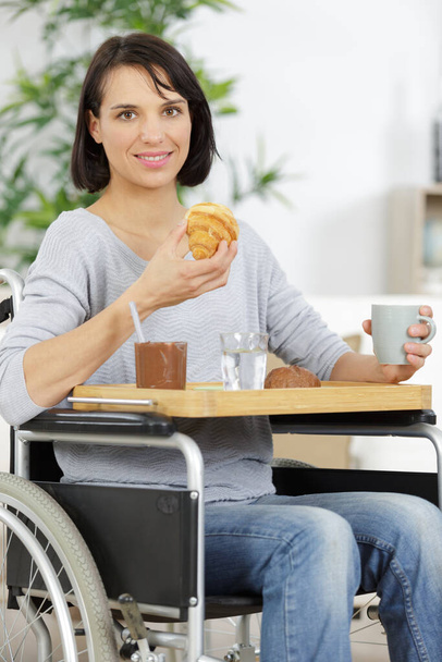 disabled woman in wheelchair having croissants - Foto, imagen