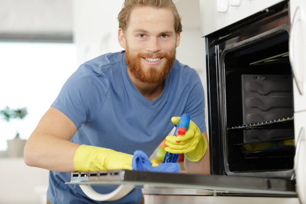 man cleaning oven in kitchen - Zdjęcie, obraz