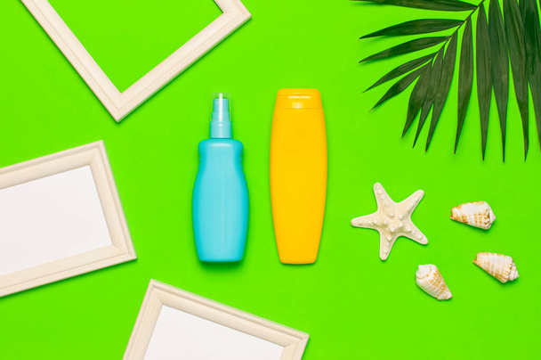 Sun protection Summer background vacation travel concept Yellow blue bottles of sunscreen cream tropical palm leaves shells starfish on green background top view flat lay copy space. Summer cosmetics. - Фото, изображение