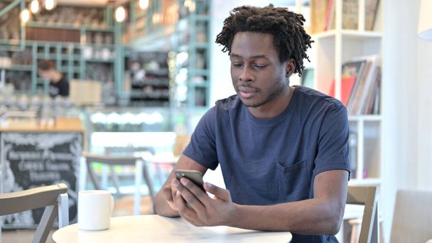 Utilisation du smartphone par African Man dans Cafe
 - Photo, image