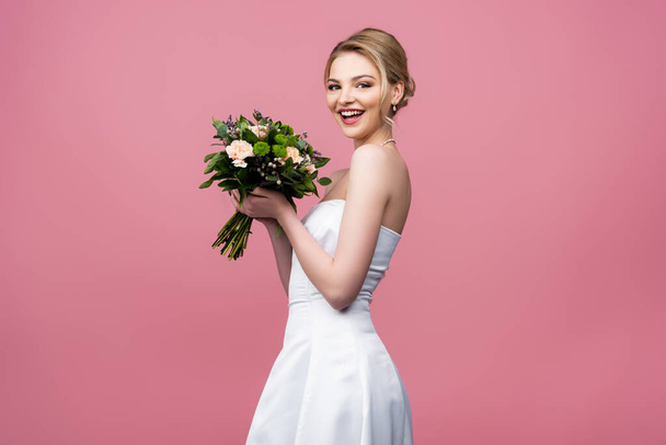 sposa allegra in abito da sposa bianco con fiori isolati su rosa  - Foto, immagini