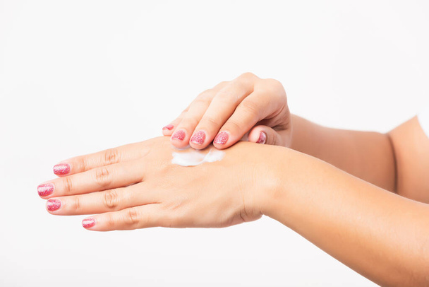 Closeup young Asian woman applying lotion cosmetic moisturizer cream on her behind the palm skin hand, studio shot isolated on white background, Healthcare medical and hygiene skin body care concept - Photo, Image