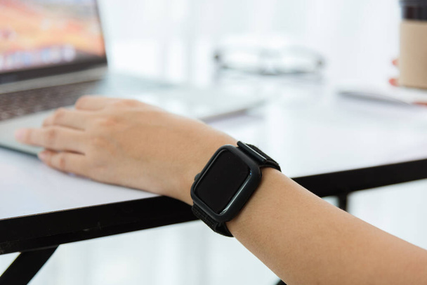 Trabalho em casa, Happy Asian jovem empresária usar mão dedo touch screen computador portátil moderno ela usa um relógio inteligente no foco do pulso em smartwatch
 - Foto, Imagem