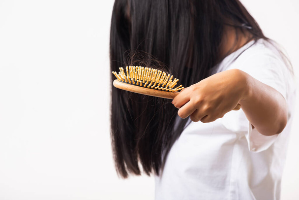 Asian woman unhappy weak hair she shows hairbrush with damaged long loss hair in the comb brush on hand, studio shot isolated on white background, medicine health care concept - Фото, изображение