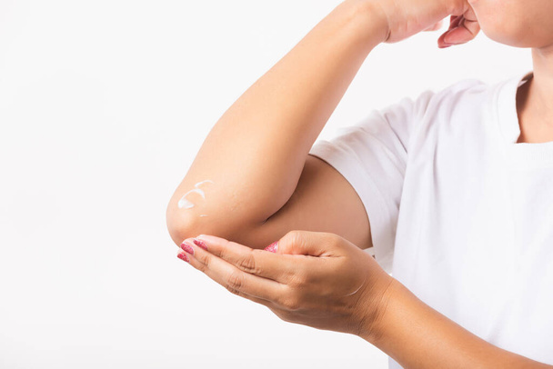 Closeup young Asian woman applies lotion cream on her elbow, studio shot isolated on white background, Healthcare medical and hygiene skin body care concept - Photo, image