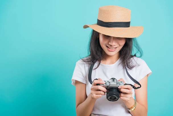 Traveler tourist happy Asian beautiful young woman smile in summer hat standing with mirrorless photo camera, shoot photo in studio on blue background with copy space for text - Foto, afbeelding