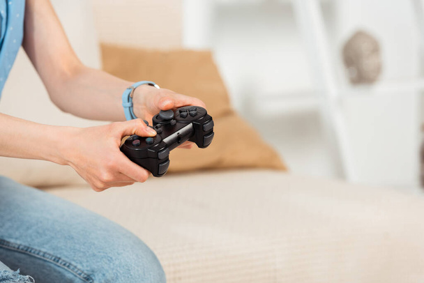 KYIV, UKRAINE - JUNE 4, 2020: Cropped view of woman holding joystick while playing video game at home  - Foto, afbeelding