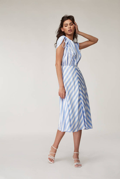 Sexy fashion model beautiful woman pretty face natural makeup, tanned skin body  wear summer collection clothes style for romantic date walk casual trendy light silk in white blue stripes long dress. - Фото, зображення