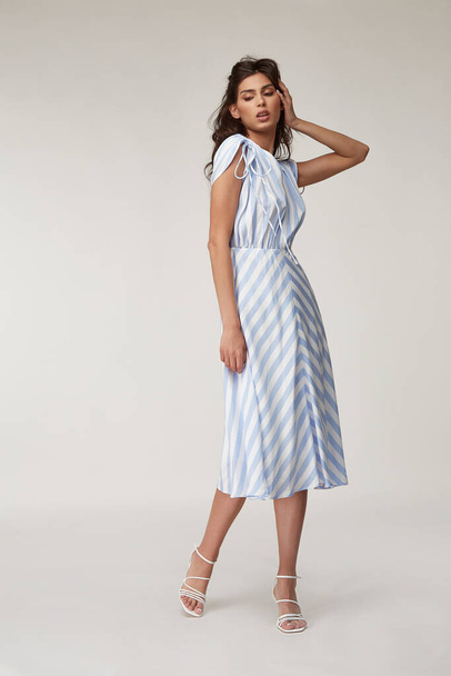 Sexy fashion model beautiful woman pretty face natural makeup, tanned skin body  wear summer collection clothes style for romantic date walk casual trendy light silk in white blue stripes long dress. - Photo, Image