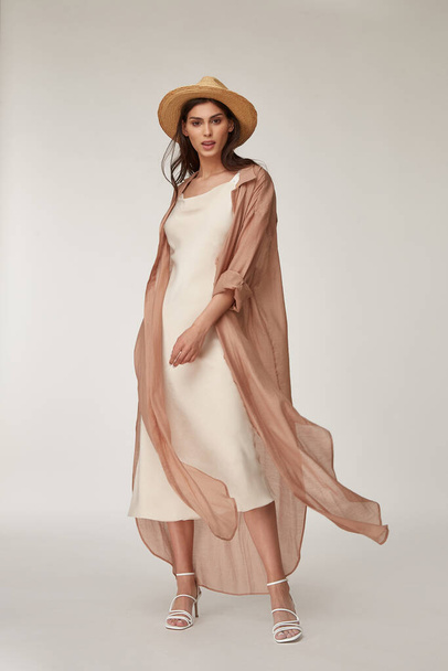Beautiful woman fashion model makeup brunette hair perfect body shape tanned skin wear clothes summer collection organic silk dress and long shirt cape stylish sandals shoes, accessory hat romantic. - Фото, зображення