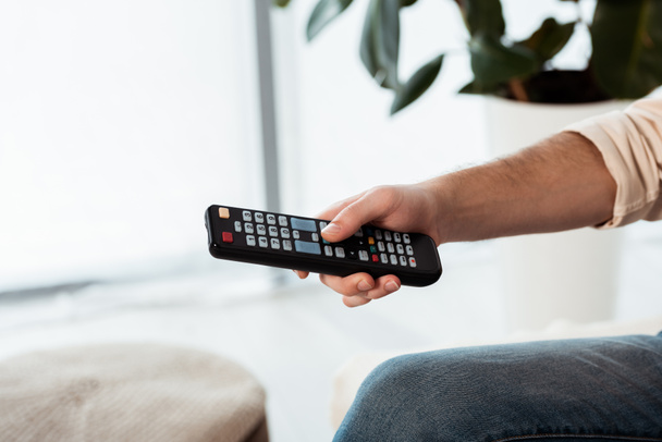 Cropped view of man holding remote controller at home - Photo, Image