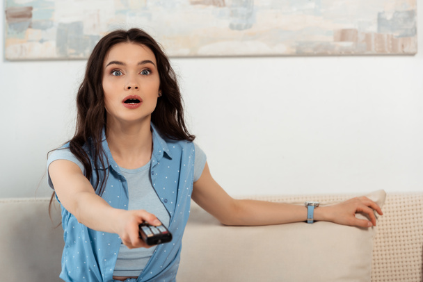Enfoque selectivo de mujer excitada sosteniendo mando a distancia en casa
  - Foto, Imagen