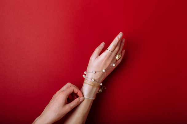 Kobieta zakłada biżuterię na rękawiczki ochronne przed COVID-19 izolowane na czerwonym tle - Zdjęcie, obraz