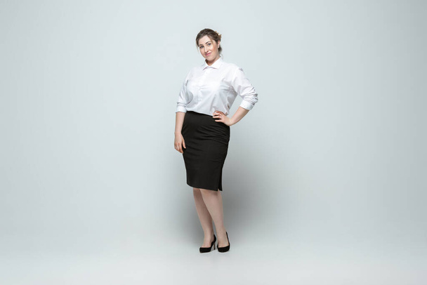 Young caucasian woman in office attire on gray background. Bodypositive female character. plus size businesswoman - Fotó, kép