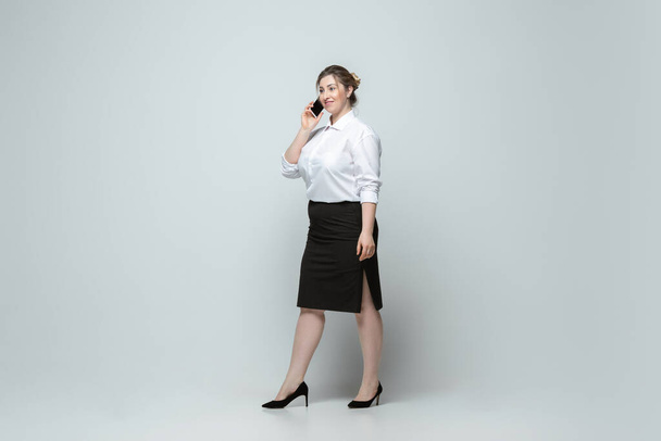 Jeune femme caucasienne en tenue de bureau sur fond gris. Caractère féminin positif au corps. plus taille femme d'affaires - Photo, image