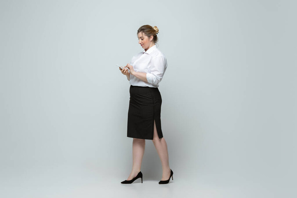 Молода біла жінка в офісному одязі на сірому фоні. Тілесно-позитивний жіночий характер. плюс розмір бізнес-леді
 - Фото, зображення