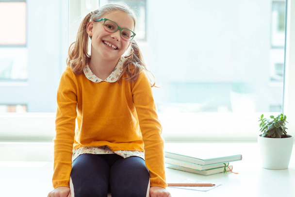 Portrait of funny teen girl in glasses sitting on desk and at holidays - Foto, imagen