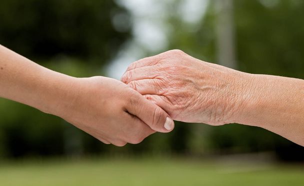 Las manos de ayuda para el cuidado de ancianos en el hogar al aire libre
 - Foto, imagen