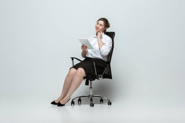 Young caucasian woman in office attire on gray background. Bodypositive female character. plus size businesswoman - Fotó, kép