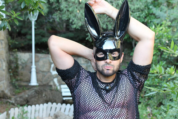 primer plano retrato de guapo joven en gay orgullo traje con conejo máscara y boca plug en la calle
 - Foto, Imagen