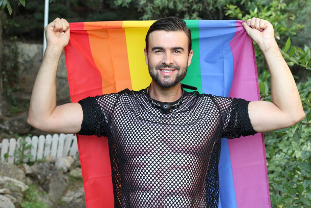 крупным планом портрет красивого молодого человека в гей-костюме гордости с флагом на улице
 - Фото, изображение