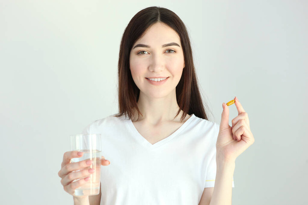 Jonge vrouw neemt visolie capsules thuis - Foto, afbeelding