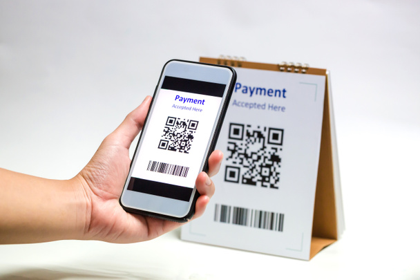 Mit dem Smartphone in der Hand scannt man QR-Code-Zahlungen auf weißem Hintergrund. Das Konzept der bargeldlosen Technologie oder des digitalen Zahlungsverkehrs. - Foto, Bild