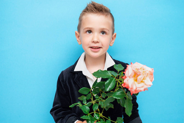 Маленький усміхнений дошкільник у костюмі з трояндою в руці
 - Фото, зображення
