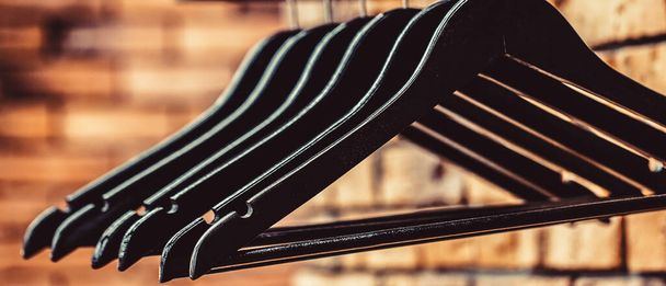 Many wooden black hangers on a rod. Store concept, sale, design, empty hangers. Wooden coat hanger clothes - Photo, Image