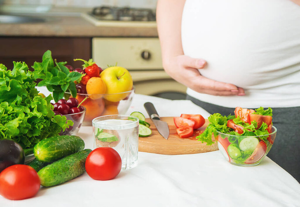 A pregnant woman eats vegetables and fruits. Selective focus. Food. - Фото, изображение